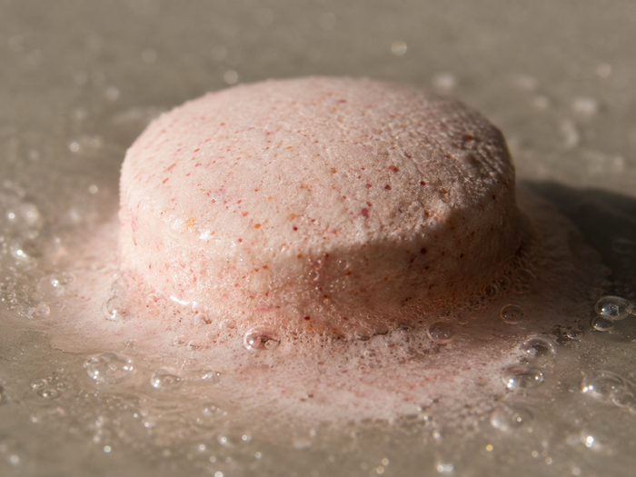 A blush-pink tablet dissolving
